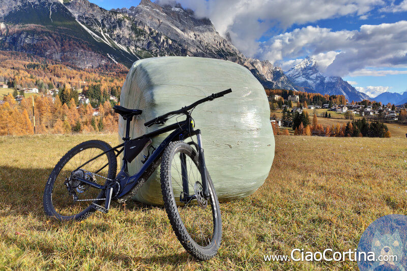 Ebike appoggiata su balla di fieno con il monte Faloria sullo sfondo